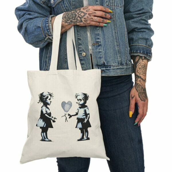 A woman holding a Children and Girl Street Art Natural Cotton Canvas Tote Bag with a tote bag mockup of two little girls on it. A woman holding a Children and Girl Street Art Natural Cotton Canvas Tote Bag with a tote bag mockup of two little girls on it.