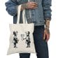 A woman holding a Children and Girl Street Art Natural Cotton Canvas Tote Bag with a tote bag mockup of two little girls on it.