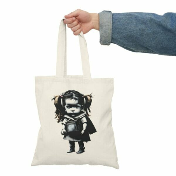 A woman holding a Children and Girl Street Art Natural Cotton Canvas Tote Bag with a girl holding a gun print design. A woman holding a Children and Girl Street Art Natural Cotton Canvas Tote Bag with a girl holding a gun print design.