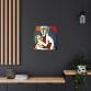 A modern room with a dark wall showcases the Mother's Love Cubism Art Canvas, reminiscent of Picasso's abstract style, depicting two abstract figures. The space is complemented by wooden accents, a hanging light, and a plant on a cabinet.