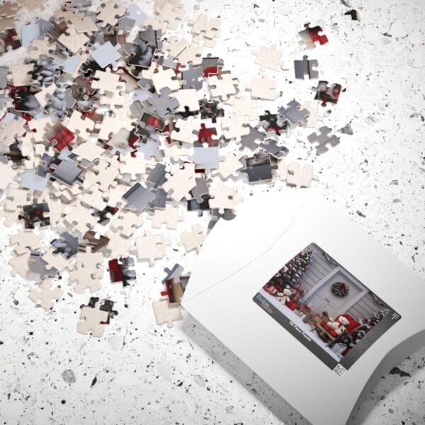 Puzzle pieces from the Christmas Doorway Puzzle set are scattered across a speckled surface, with a partially opened box revealing a festive scene. Puzzle pieces from the Christmas Doorway Puzzle set are scattered across a speckled surface, with a partially opened box revealing a festive scene.