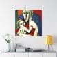 The Mother's Love Cubism Art Canvas, featuring a geometric abstract design in the style of Picasso's cubism, adorns a white wall above a shelf holding a yellow lamp, books, and a vase filled with flowers.