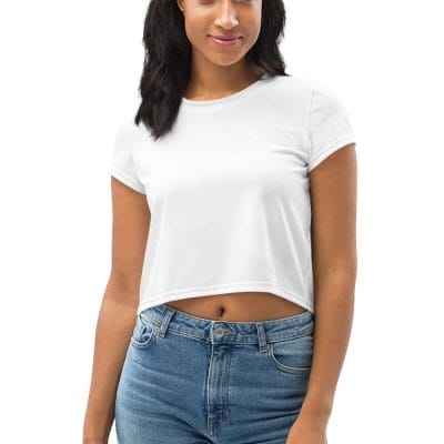 A person faces forward wearing the All-Over Print Crop Tee, a white short-sleeve crop top, paired with blue jeans and one arm relaxed at their side.